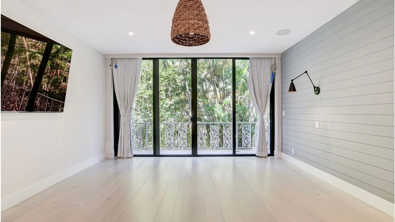 Impact sliding glass doors opening a living room onto a shaded balcony
