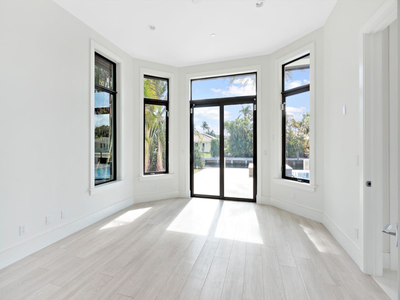 Bright South Florida living room with impact windows overlooking palms and water