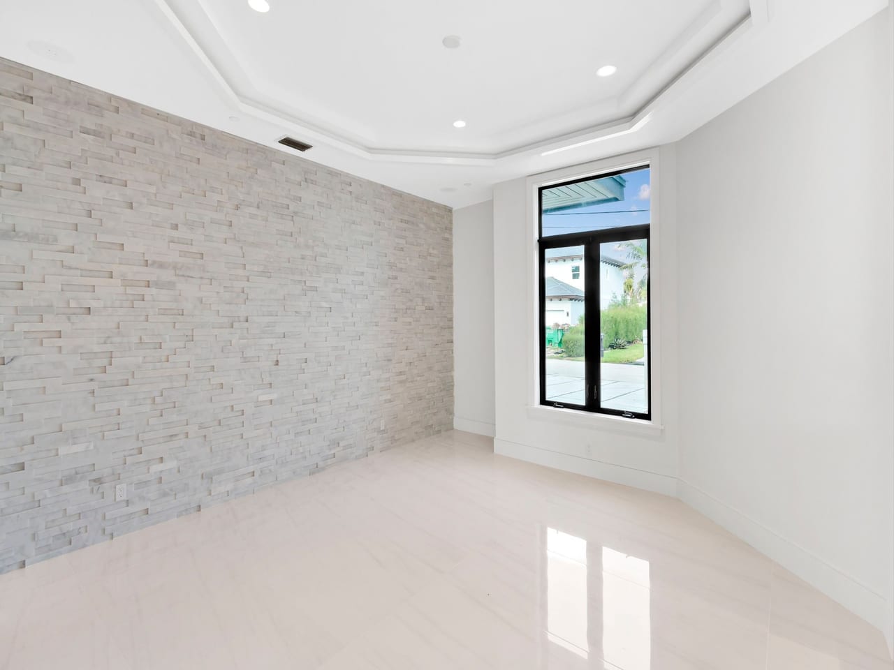 A black-framed impact window beside a stone feature wall in a finished room