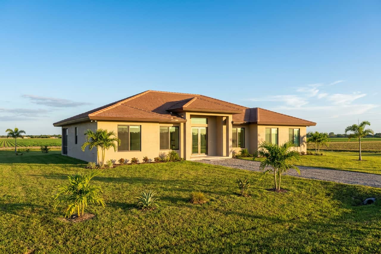 A newer single-storey concrete-block home of the kind built around Homestead, under open sky, with impact-rated windows and a glass door